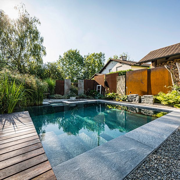 Naturpool mit Steinbegrenzung, Steinstufen und Holzsteg